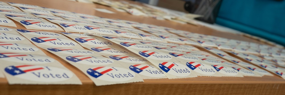 Dozens of "I Voted" stickers laid out in rows on a table.