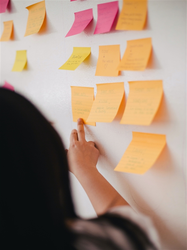 person pointing to post its on board