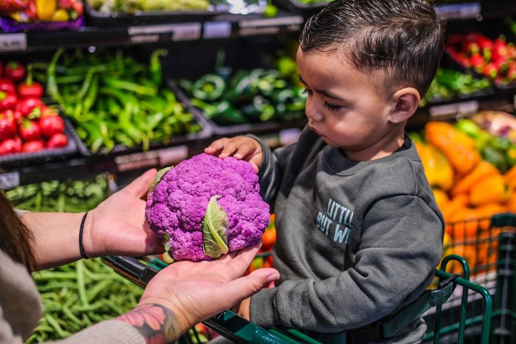 Mom handing child healthy food in grocery store